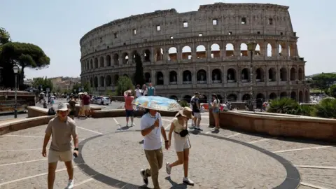Reuters A person holds an umbrella as people walk near the Colosseum during a heatwave across Italy, as temperatures are expected to rise further in the coming days, in Rome, Italy August 3, 2026.
