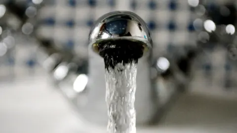 PA Media Close up photograph of a shiny, silver-coloured running tap against a blurred background