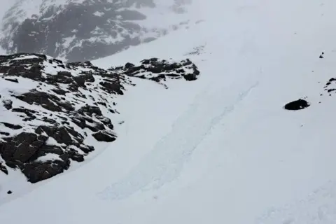 SAIS Lochaber The debris is made up of big lumps of snow that has slid down a snow-covered slope. There are rocky outcrops nearby.