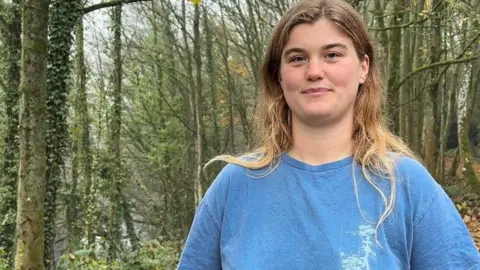 A woman in a blue t-shirt in some woodland