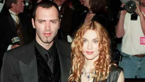 Getty Images Pasangan ini menghadiri banyak acara bersama, termasuk pesta Oscar Vanity Fair tahun 1998. Ciccone mengenakan tuksedo hitam dan Madonna mengenakan gaun tanpa lengan hitam abu-abu dengan garis leher menjuntai.