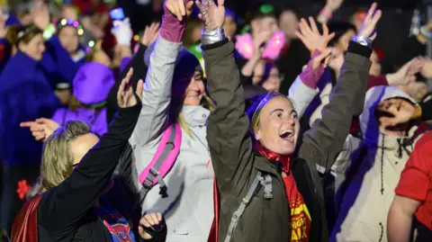 Nick Butcher Photography/St Elizabeth Hospice A group of people during an event. They raise their hands in celebration. 
