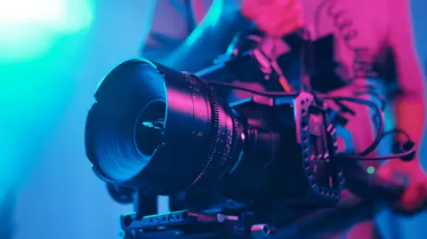 Getty Images Production crew holding a film camera