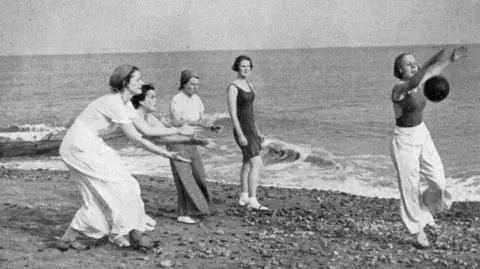 Bexhill Museum A black and white photography of Augusta Victoria College students playing on Bexhill beach.