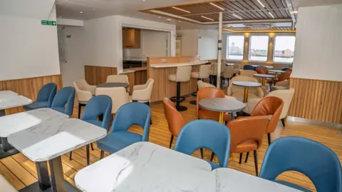 LCRCA A lounge area featuring grey marble designed tables, with blue, beige and brown chairs. 