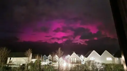 Pink skies lit up the dark sky over Westward Ho!. The northern lights are above residential houses. 