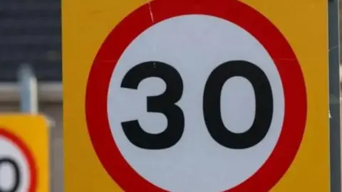 the number 30 on a white circular background, with a red rim and and a futher yellow backfound