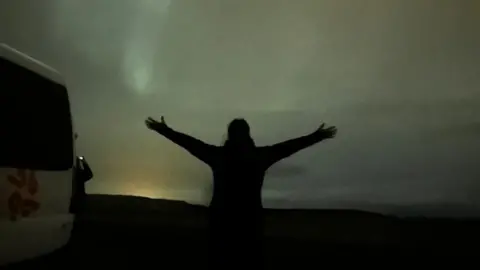 Dee Harrison A silhouette of a woman against the backdrop of the Northern Lights in Iceland