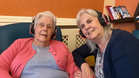 Resident Audrey with her daughter Sue Tripp, as they listen to music through headphones.