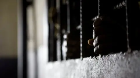 Glenna Gordon/Amnesty International Prisoner's hands on the bars in his cell door, Liberia - 2011