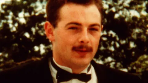 A file photo of Tony Doris, he has short brown hair and a brown moustache and is pictured from the shoulders up wearing a black suit jacket, white formal shirt with wing tip collar and black bow-tie.