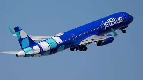 Blue plane in the sky with "JetBlue" written on the side