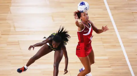 Getty Images Serena Guthrie pictured in an action shot playing netball. Another player is visible and Guthrie is winning possession of the ball. 