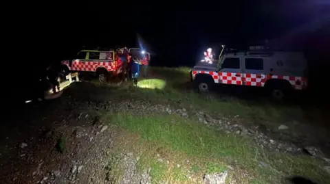 Patterdale Mountain Rescue Team Mountain rescue teams use trucks' lights to see in the dark evening conditions on one of the fells in the Lake District.