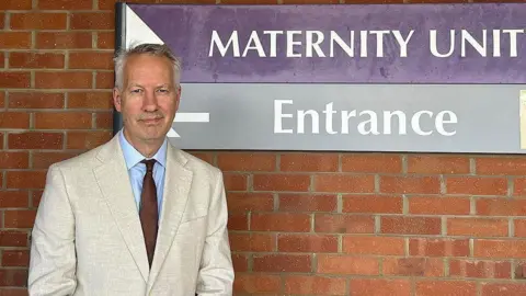 Gideon Amos looking at the camera outside the entrance of Musgrove Park Hospital's Maternity Unit