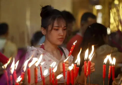 Nyein Chan Naing/Epa-Efe Seorang wanita menyalakan lilin di dalam kuil Cina di Yangon, Myanmar 