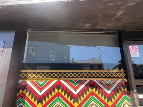 Shows damage to a window which is painted in bright colours