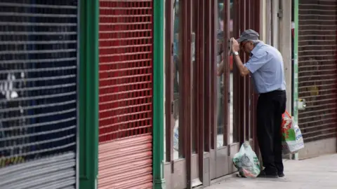 Getty Images A man looks into a closed coffee shop