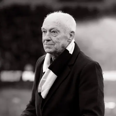 Wolves A black and white photo of Terry Wharton as an older man, wearing a suit and a black and white scarf.