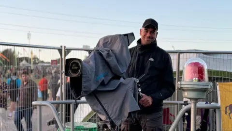 Man stood with big camera on crane platform