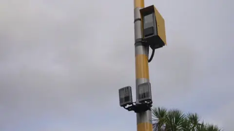 A bright yellow speed camera with two sensors underneath 