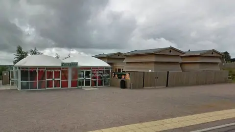 Google Butterfly World when it was open, showing wooden structures, like giant beehives, an entrance and a sign that says Step Into Butterfly World