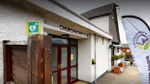 Tony Kavanagh Outside Churchdown Club, with a view of the front doors and the club sign above them