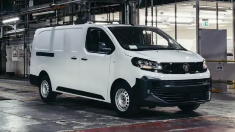 Stellantis A white van in a factory, with glass windows behind it