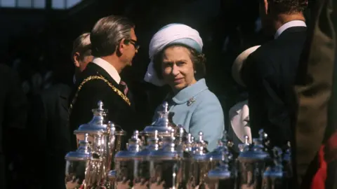 Alamy The Queen looks at some of the trophies on display at Meadowbank Stadium in Edinburgh during her 1977 jubilee tour