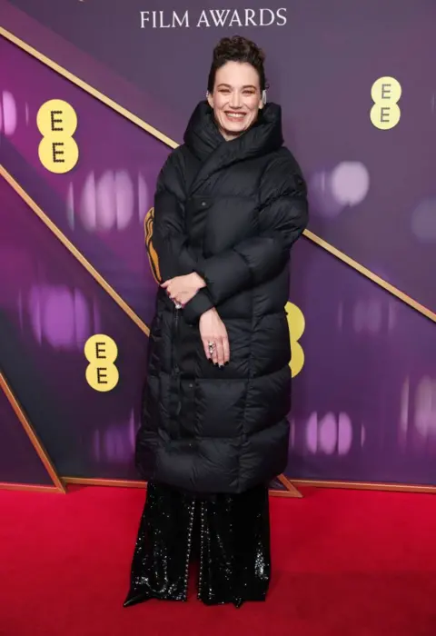 Getty Images Coralie Fargeat in a black puffa coat over her long, black outfit 