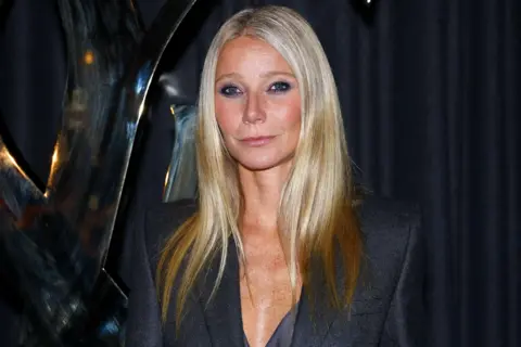 Getty Images Gwyneth Paltrow looking at camera at a red carpet event. She wears a navy blazer dress and has long blonde hair. 