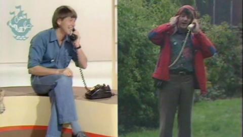 A split screen image - on the left John Noakes is sitting down in a studio, speaking into a phone. On the right, Peter Purves is standing outside in the rain, wearing a red raincoat and speaking into a telephone reciever.