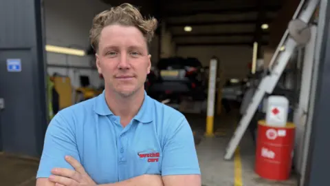 Lewis Mennie from Westhill Cars is standing at his garage 