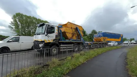 Traffic on the A66 at Penrith, waiting to enter Kemplay Bank roundabout. Several vehicles are in the queue including two lorries, a van and several cars.