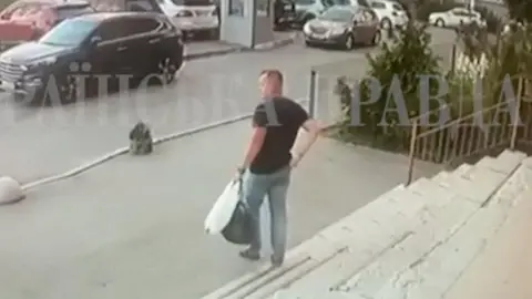 A still from CCTV footage prior to the killing in Kyiv on Thursday, which shows a man wearing jeans and a dark t-shirt walking out of a building down a set of steps towards a city car park.