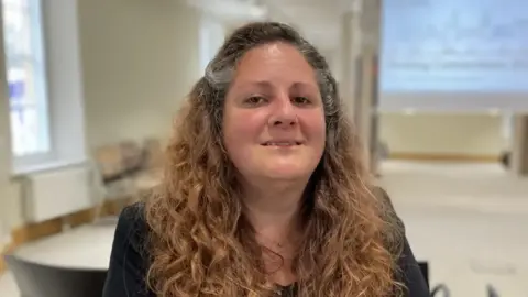 Ben Schofield/BBC Elisa Meschini is wearing a black top and smiling at the camera.