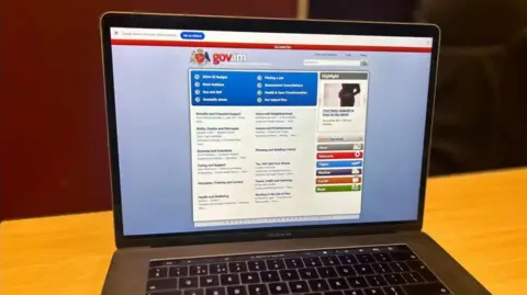 A laptop showing the government website, which is predominately blue with the government crest and gov.im at the top.