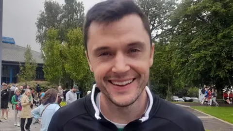 Soccer coach Coach Gavin Carlin has short brown hair and is wearing a black shirt