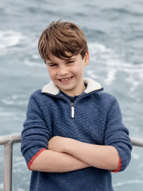 Matt Porteous A grinning Louis is shown leaning with his arms folded against a metal barrier, with the sea as the backdrop.