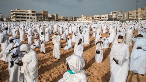 AFP Followers of the Layene community wearing protective masks take place on the beach in front of the Yoff Layene Mosque, during the Islamic festivity of Korite in Dakar, Senegal, on May 24, 2020,