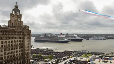 Cunard Cunard cruise liners sailing on the River Mersey near the Royal Liver Building and thousands of people lining Liverpool's waterfront while the Red Arrows performed a fly-past to celebrate Cunard's 175th anniversary.