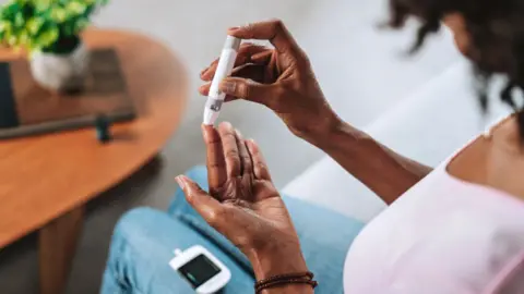 Woman tests uses diabetes pen in the tip of her left index finger