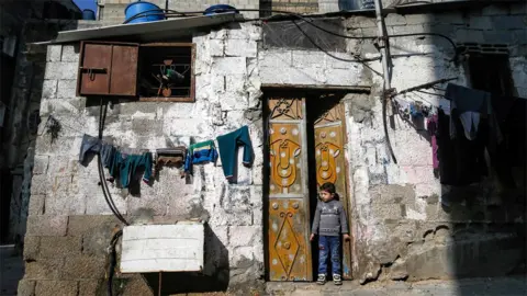 AFP A Palestinian boy stands in the door of a house at the al-Shati refugee camp in Gaza City (28 January 2020)