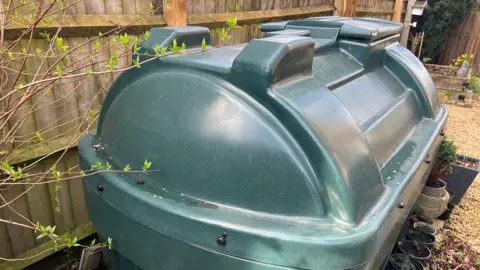 A green plastic box with a curved top, with a fence behind it.