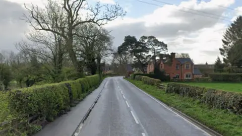 Google A country road with hedges and trees on both sides and a house in the distance