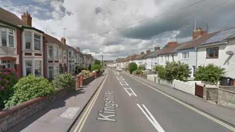 Google A Google Maps screenshot of the road, taken from uphill. It is a sunny day with some clouds, and the street is made up of lots of terraced houses. 