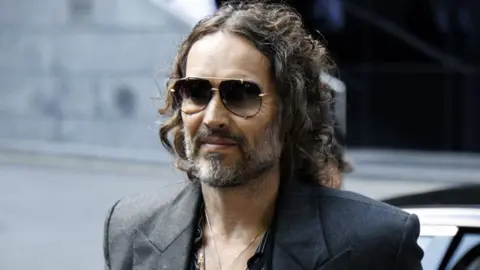 Russell Brand arriving at court in dark sunglasses