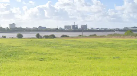 Google Shot of the ICI site taken far away. The plant can be seen in the distance which is surrounded by low, green fields.