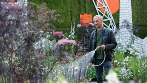 RHS/Georgi Mabee Nigel Dunnett waters his garden at the RHS Chelsea Flower Show