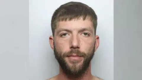 Derbyshire Police Custody photo of David Oswald - he has brown hair and brown facial hair